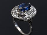 an oval blue sapphire and diamond ring on a black surface