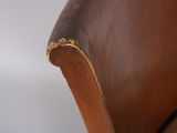close up of a wooden chair with a brown leather seat