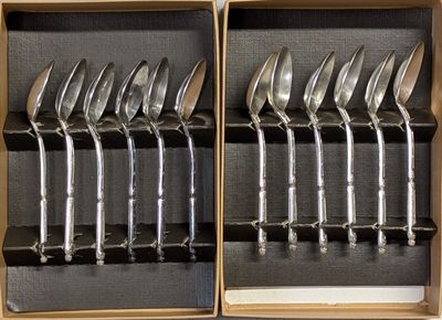 six cuillères en argent dans une boîte en bois posée sur une table