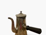 a silver coffee pot with a black handle on a white surface