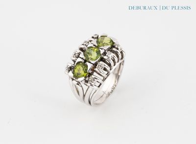 un gros plan d'une bague ornée de pierres vertes sur fond blanc