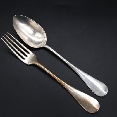 two silver spoons and a fork on a black background