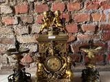 une horloge en or posée sur une table en marbre, près d'un mur en briques