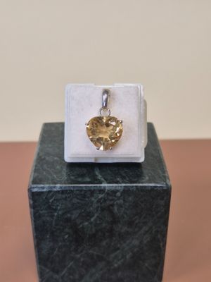 une image représentant un pendentif en forme de cœur en or posé sur un bloc de marbre