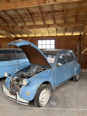 une petite voiture bleue, le capot ouvert, dans un garage