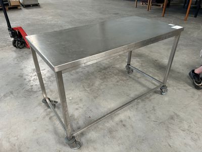 une table en acier inoxydable montée sur roulettes dans un entrepôt