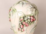 a white vase with a bunch of berries on it