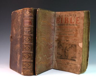 un vieux livre ouvert posé sur une table, à côté d'un autre livre