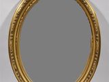 un miroir ovale doré, doté d'un cadre décoratif et orné d'un motif floral