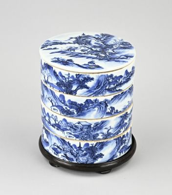 une boîte en porcelaine bleue et blanche avec un socle noir sur fond blanc