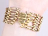 gold tone bracelet with links and clasps on a woman ' s wrist