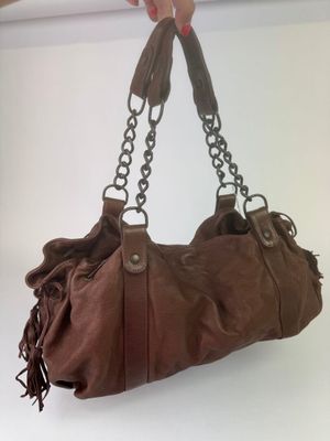 someone is holding a brown purse with a chain hanging from it