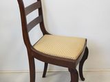 a wooden chair with a cushion on it in the corner of a room