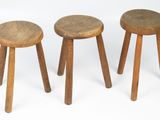 three small wooden stools sitting next to each other on a white surface