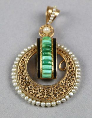 un gros plan d'un pendentif doré et vert orné de perles