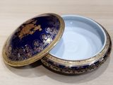 a blue and gold box with a lid on a wooden table