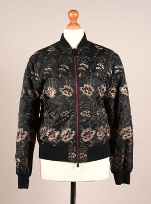 La veste bomber est noire et présente un motif floral.