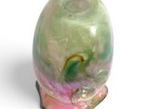 a green and pink vase sitting on a white surface