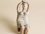statue représentant une femme assise sur le dos, les mains derrière la tête