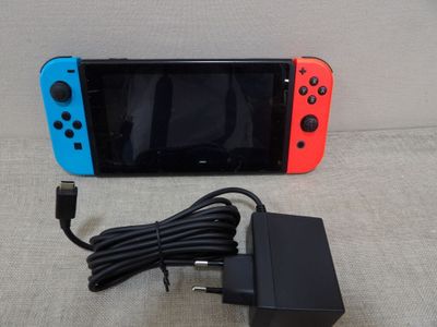 une Nintendo Switch Lite avec un chargeur branché dessus