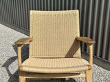 a brown chair sitting on top of gravel next to a metal wall