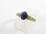 a close up of a gold ring with a blue stone and diamonds