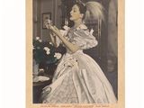 une vieille photo d'une femme en robe blanche tenant une fleur