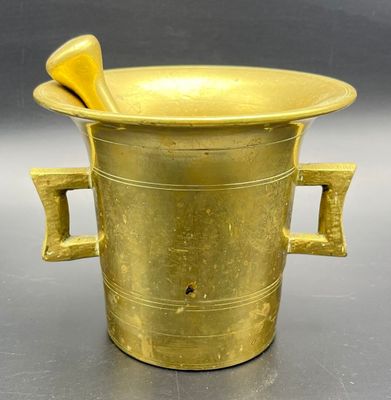 a gold vase with two handles and a wooden spoon in it