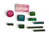 Plusieurs pierres précieuses de différentes couleurs sont disposées sur une surface blanche.
