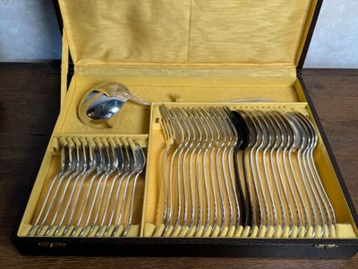de nombreuses fourchettes et cuillères dans un coffret posé sur une table