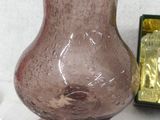 a pink glass vase sitting on a table next to a box of candy