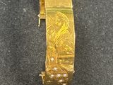 gros plan d'un bracelet en or sur une surface noire