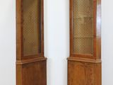 pair of antique wooden display cabinets with glass doors in a white room