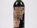une vieille bouteille de vin posée sur une surface blanche