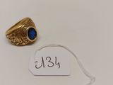 une bague en or sertie d'une pierre bleue est posée sur une étiquette