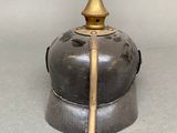 a metal helmet with a golden top on a gray surface