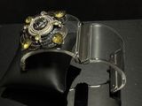 a silver cuff with a black and yellow flower on it