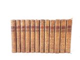 six old books are lined up in a row on a white surface