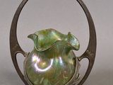 a green vase sitting on top of a metal stand