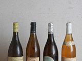 des bouteilles de vin alignées sur une table en bois, avec un mur en arrière-plan
