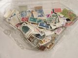 un récipient en plastique rempli de timbres-poste posé sur une table