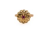 a gold ring with a ruby stone surrounded by filigree filigree