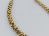 a close up of a gold chain necklace on a white surface