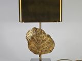 une lampe à feuille d'or sur un pied noir, avec un abat-jour doré