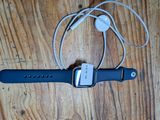 une Apple Watch et des écouteurs branchés sur un chargeur