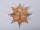 a gold starburst hanging on a white wall