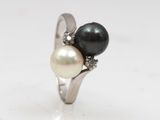 a close up of a ring with two pearls and diamonds