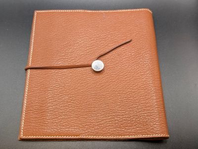a close up of a brown leather journal with a button on it