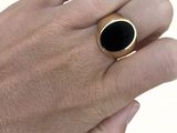 la main d'un homme tenant une bague sertie d'une pierre noire