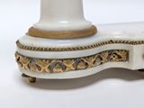 a white and gold vase on a stand on a white surface